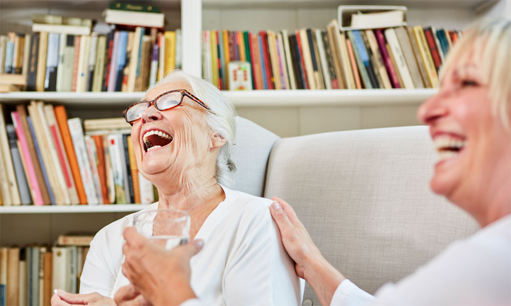 Woman laughing with a hand on her shoulder